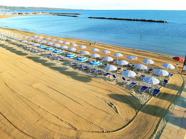 Spiaggia con ombrelloni blu e bianchi.