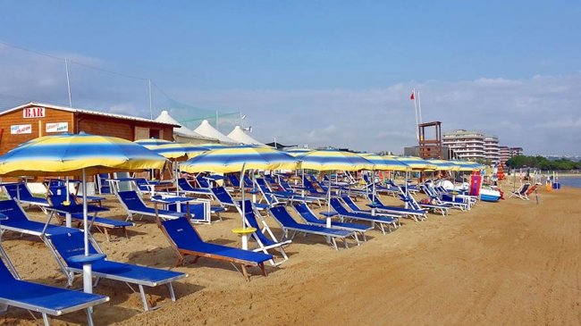 Lettini e ombrelloni su una spiaggia di sabbia.