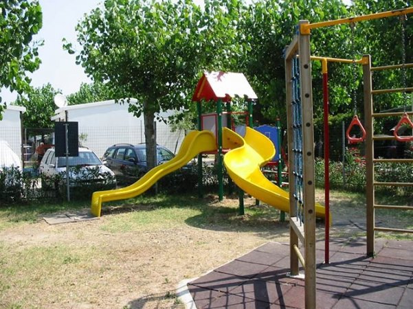 Scivolo giallo in un parco giochi con alberi.