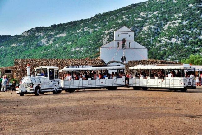 Un trenino bianco vicino a una chiesa.