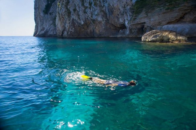 Persona fa snorkeling in mare limpido.