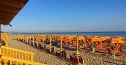 Vista laterale di una spiaggia con ombrelloni arancioni.