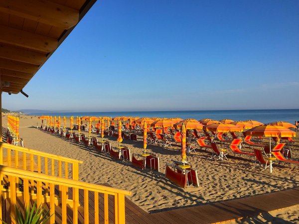 Spiaggia con file di ombrelloni arancioni.