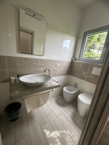 Bagno moderno con lavabo sospeso e finestra.