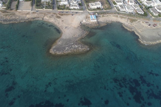 Vista aerea di una spiaggia con mare azzurro.