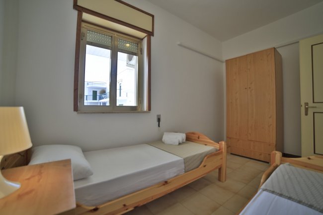 Stanza con due letti singoli e armadio in legno.