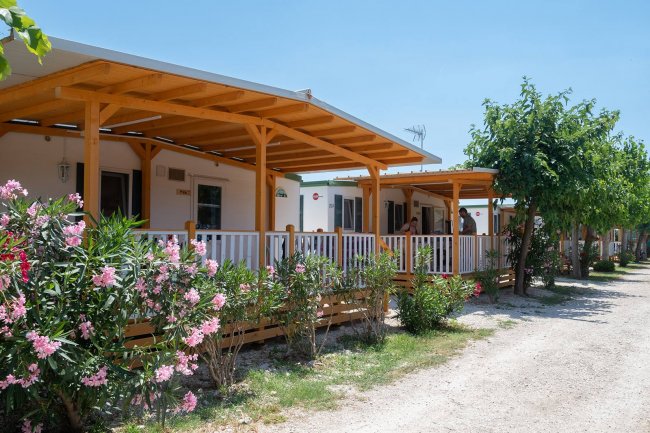Bungalow con veranda in legno e fiori davanti.