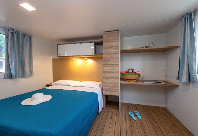 Camera con letto matrimoniale, tappeto, e mensole.