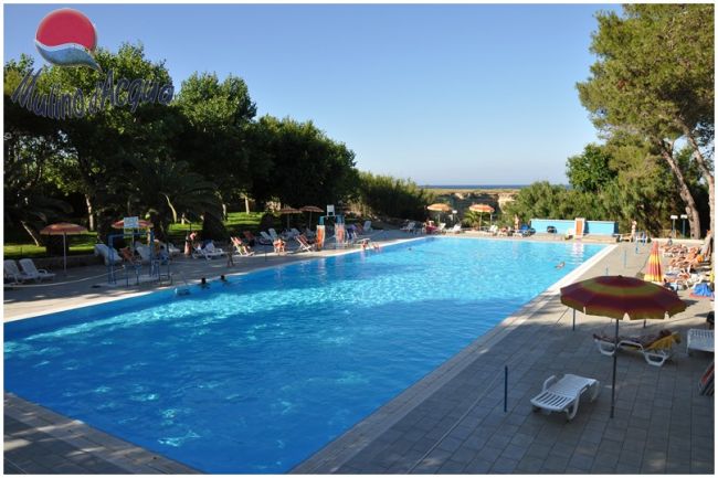 Piscina all'aperto circondata da lettini e ombrelloni.
