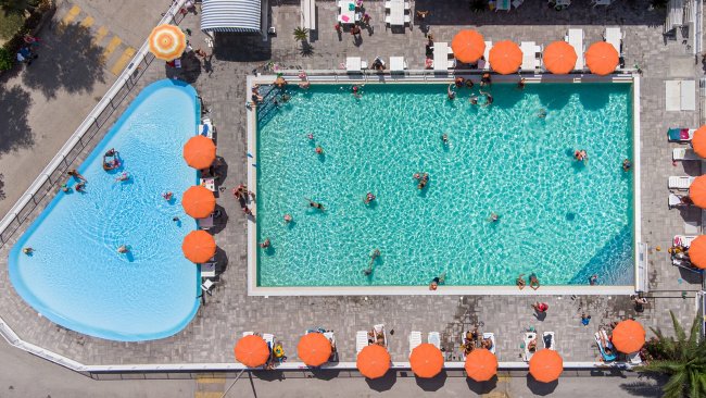 Vista aerea di due piscine con ombrelloni arancioni.