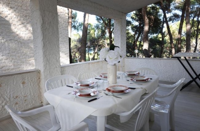 Tavolo da pranzo all'aperto con piatti e fiori.