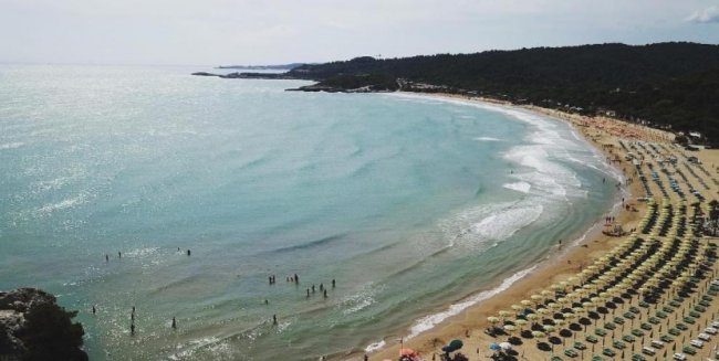 Spiaggia con ombrelloni e bagnanti in mare.