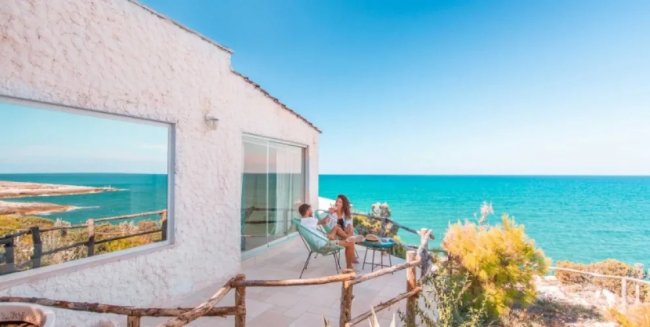 Terrazza sul mare con due persone sedute.
