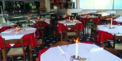 Ristorante elegante con tavoli apparecchiati, candele accese e tovaglie rosse e bianche.