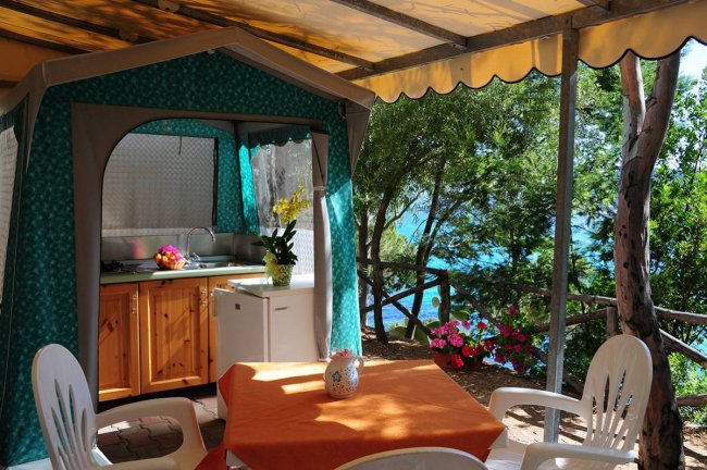 Un patio con tavolo, sedie e cucina esterna.