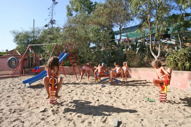 Bambini che giocano in un parco giochi sabbioso.