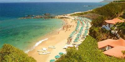 Spiaggia con ombrelloni, mare e scogli.