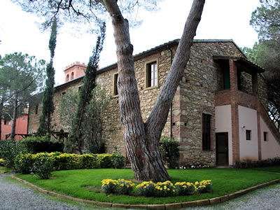 Edificio in pietra con giardino ben curato e grandi alberi.