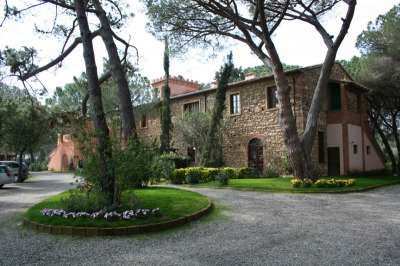 Complesso in pietra con vialetto circolare e aiuole fiorite.