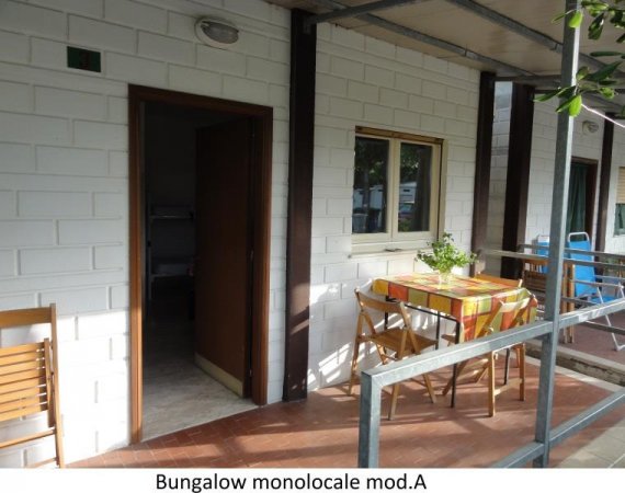 Veranda di bungalow con tavolo e sedie all'aperto.
