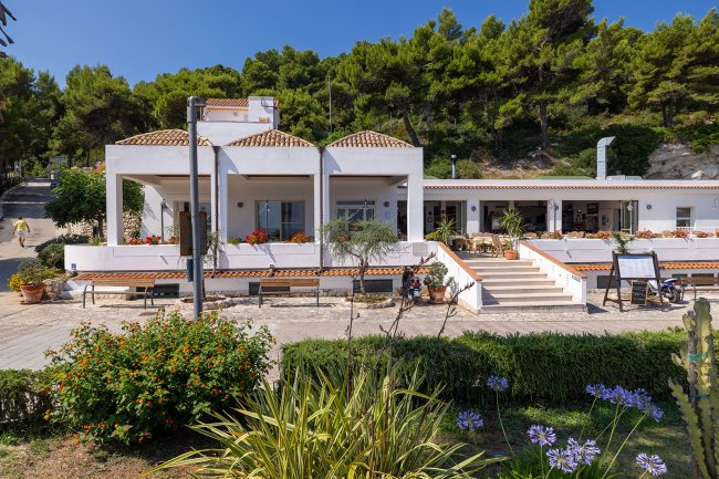Casa bianca con giardino e fiori in primo piano.