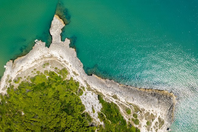 Vista aerea di una costa rocciosa e mare turchese.