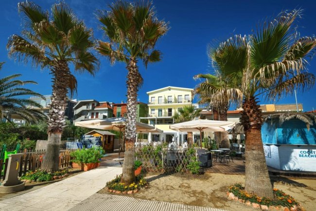 Giardino con palme e edificio sullo sfondo.