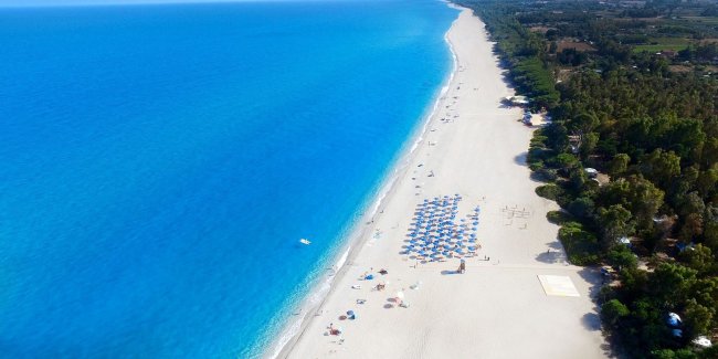 Lunga spiaggia con ombrelloni e mare blu.