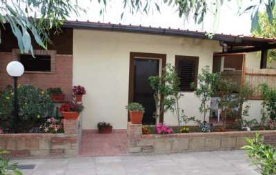 Un piccolo edificio con pareti bianche, decorato con piante e fiori in vaso.