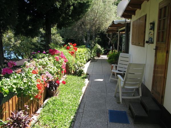 Sentiero affiancato da fiori e sedie da giardino.