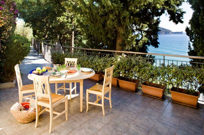 Terrazza con tavolo, sedie e vista sul mare.