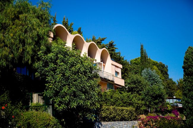 Edificio moderno tra alberi e arbusti.