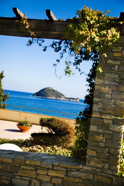 Vista di un'isola dal mare attraverso un arco di pietra.