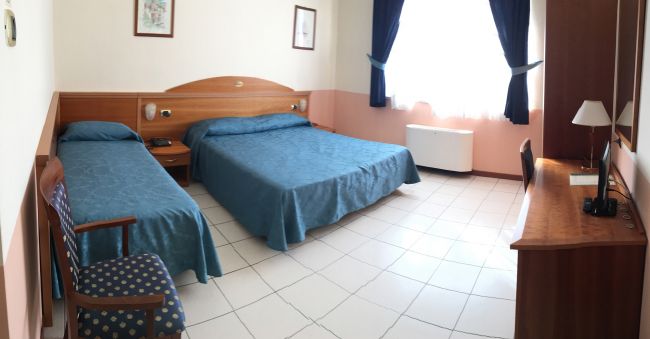 Camera d'albergo con due letti singoli blu.