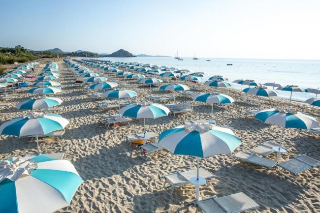 Ombrelloni bianchi e blu allineati sulla spiaggia.