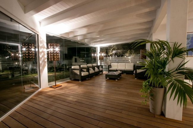 Veranda con sedie e piante, illuminata discretamente.