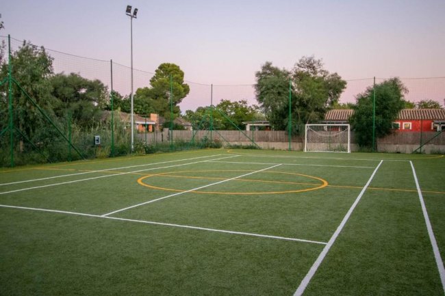 Campo sportivo all'aperto con erba artificiale e reti.