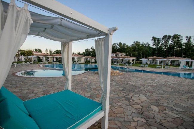 Piscina con lettini bianchi e tendaggi.