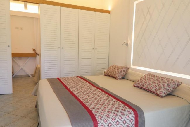 Interno di una camera con letto matrimoniale e armadio bianco.