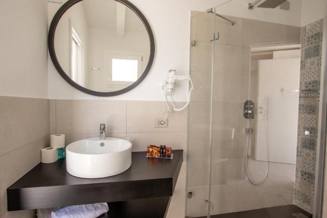 Bagno moderno con lavabo e doccia in vetro.