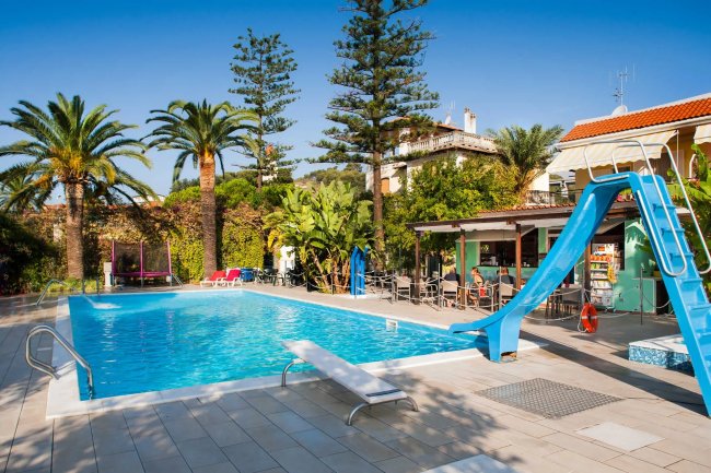 Piscina con scivolo e palme attorno.