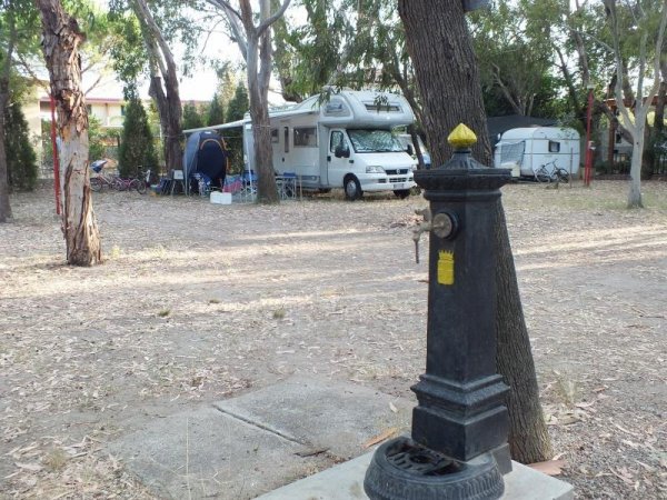 Area di campeggio con camper e fontanella.