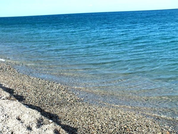 Spiaggia di ciottoli con acqua blu chiara.
