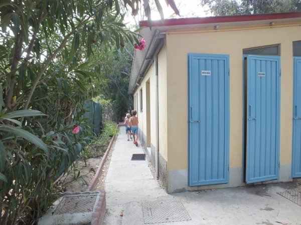 Edificio con porte blu, camminamento e fiori rosa.