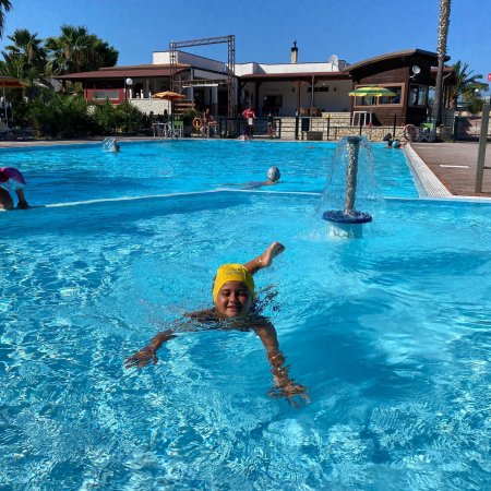 Ragazzo con cuffia gialla nuota in piscina.