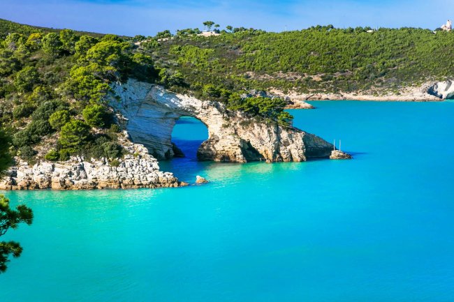 Arco naturale di roccia su mare turchese.