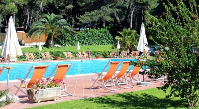 Piscina con sdraio arancioni e ombrelloni bianchi.