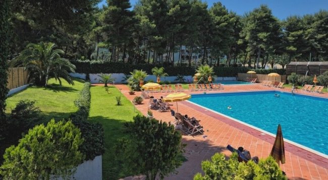 Piscina con sdraio e ombrelloni arancioni.