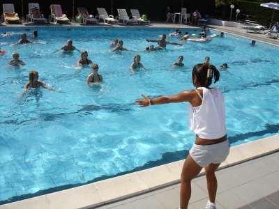 Istruttrice guida esercizi in una piscina con partecipanti in acqua.
