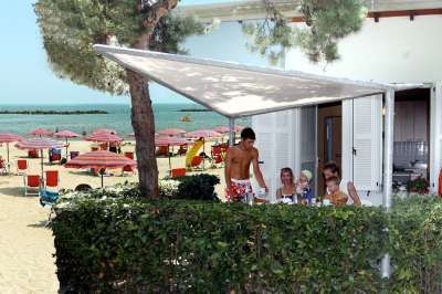 Persone sedute a un tavolo esterno vicino alla spiaggia con ombrelloni.